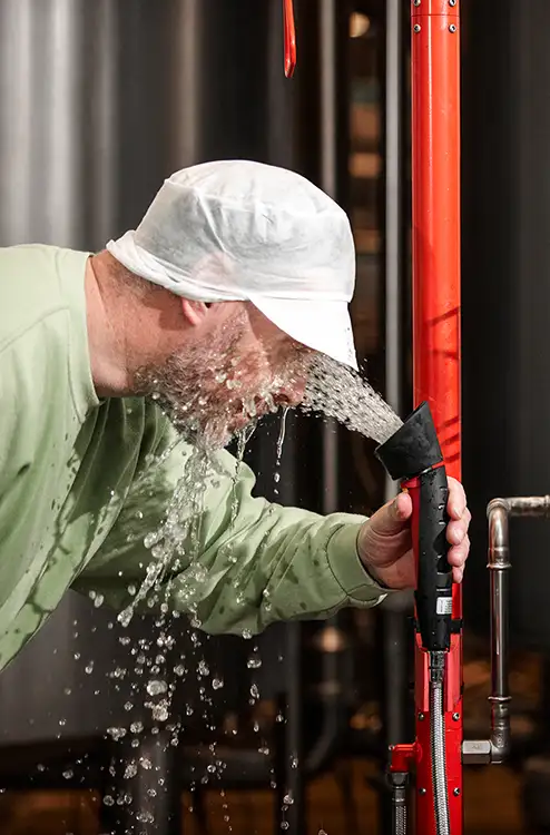 BROEN-LAB Products - combination emergency shower - picture showing man flushing his eyes with an handheld emergency shower